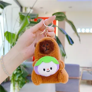 Close-up of plush capybara keychain holding a purple mangosteen toy with gold clasp