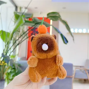 Close-up of a plush capybara keychain featuring a cute orange topper and soft texture
