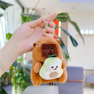 Detail of plush capybara keychain holding green avocado with golden metal clasp