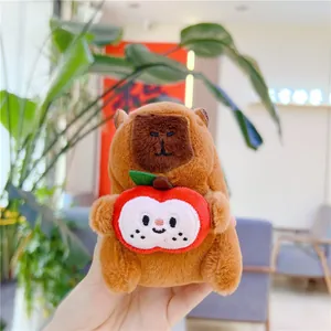 Close-up of plush Capybara keychain holding a red apple with cute facial expression