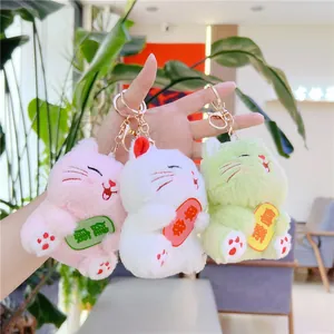 Three plush lucky cat keychains in pink, white and green with blessing charms