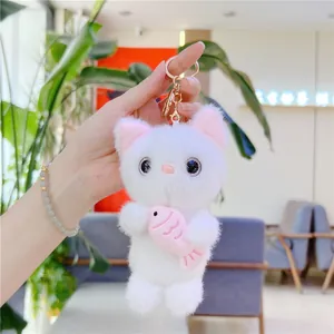 Cute white plush cat keychain holding a pink fish with golden metal keyring hook