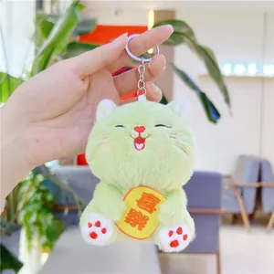 Detail of light green plush cat keychain with embroidery and Joy charm held in hand