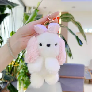 Portachiavi peluche cucciolo con orecchie lunghe e fiocco rosa in un giardino luminoso