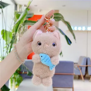 Detail of plush cat keychain holding a blue fish with soft texture and metal clip
