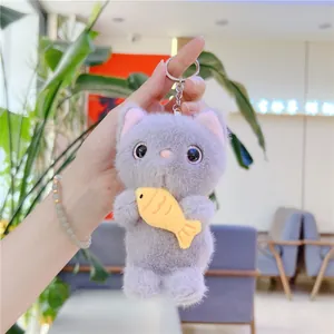 Close-up of a plush grey cat keychain holding a yellow fish with soft fur texture
