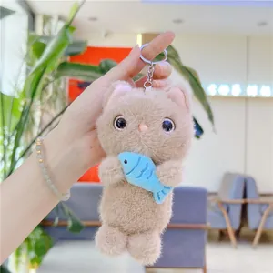 Detail of plush cat keychain holding blue fish with soft khaki fur and metal ring