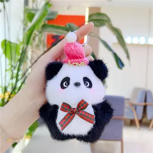 Close-up of plush panda keychain with pink LOVE hat and plaid bow held by hand