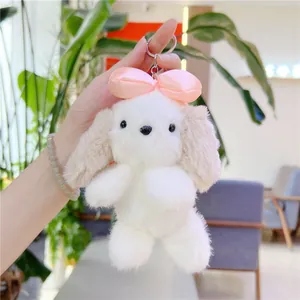 Dettaglio di un portachiavi a forma di cucciolo in peluche con fiocco rosa e gancio