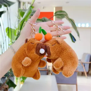 Detail of plush capybara charms with orange accents and golden metal ring clasps