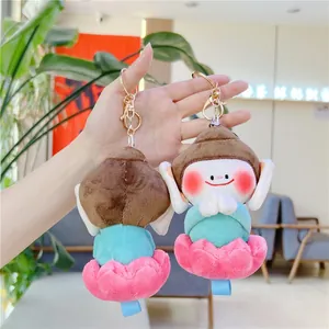 Porte-clés moine en peluche sur lotus tenu à la main dans un décor lumineux