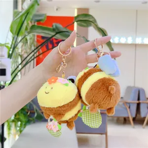 Detail of bee plush keychain with yellow stripes, floral headpiece, and metal keyring