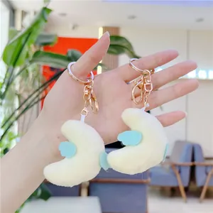 Plush moon keychain with light blue wings and gold metal hook shown in hand