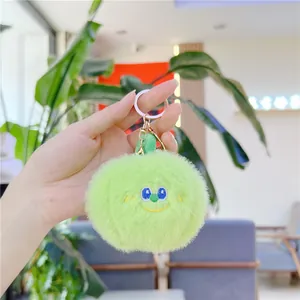Primo piano di un simpatico portachiavi in peluche verde chiaro con ricamo tenuto in mano