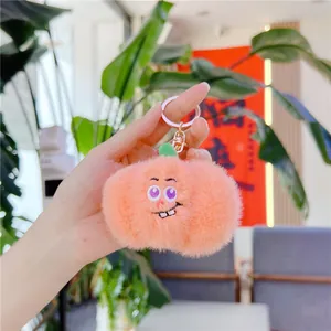 Dettaglio di un portachiavi a forma di pesca in peluche con ricamo e chiusura dorata