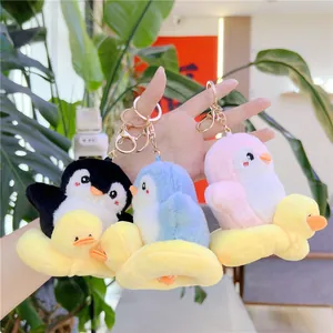 Tres lindos llaveros de pingüino de peluche con flotadores de pato amarillo en mano