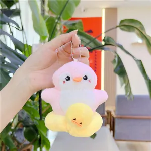Llavero de peluche pingüino rosa con flotador de pato amarillo sostenido en la mano