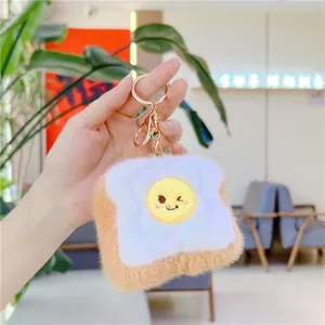 Close-up of plush toast keychain featuring a winking fried egg and gold metal ring