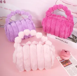 Three plush cosmetic bags in purple and pink tones with creative fluffy ball handles