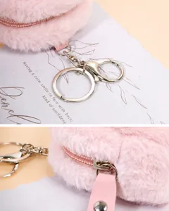 Detalle del monedero de felpa rosa con llavero plateado y tirador de cremallera de cuero