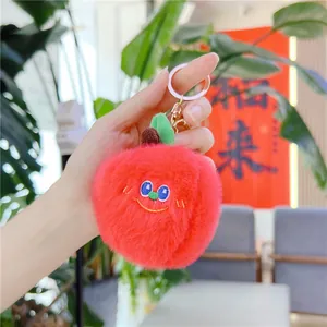 Dettaglio del portachiavi a forma di mela in peluche rosso con viso ricamato e chiusura