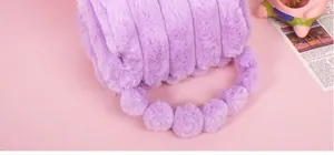 Close-up of purple faux rabbit fur makeup bag with striped texture and plush ball handle