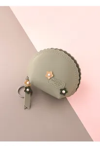 Detalle del monedero verde salvia con flor de perlas y llavero de metal plateado elegante