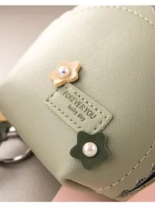 Detalle de monedero de cuero verde menta con flores decorativas y perlas brillantes