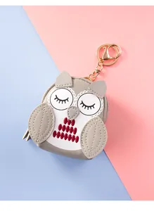 Detail of owl-shaped coin purse keychain in grey and white faux leather with gold hardware