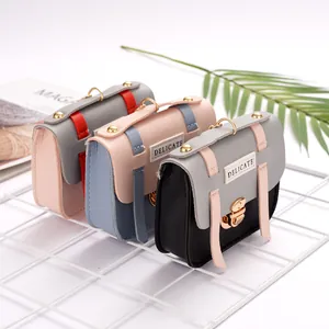 Three mini crossbody bags with metallic rings and delicate labels in assorted colors