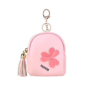 Pink mini backpack coin purse with tassel detail and heart patch on white background