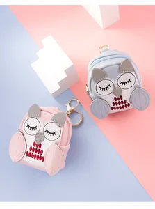 Macro shot of cute owl-shaped mini backpacks showing embroidery details and gold zippers