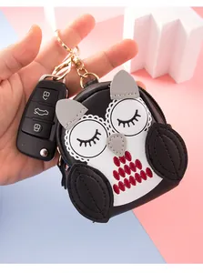 Handheld view of a cute owl mini coin purse with embroidery and gold keychain