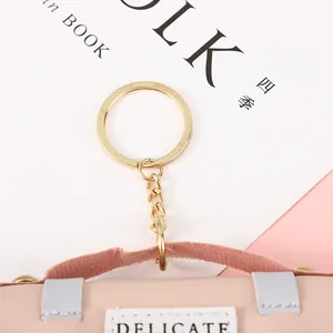 Close-up of a pink mini leather coin purse charm with delicate stitching and gold keychain