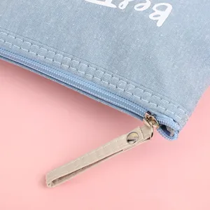 Light blue canvas makeup bag with white Bear text on a soft pink background