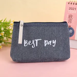 Close-up of blue denim coin purse with white best Day text and fabric zipper puller