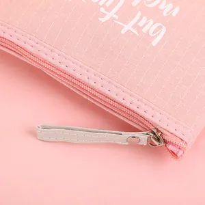 Pink minimalist makeup bag with but first text, fabric texture, and zipper detail