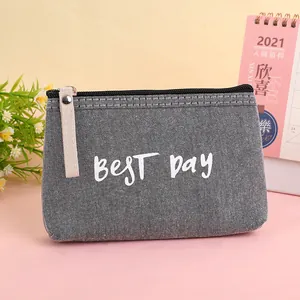 Close-up of gray canvas cosmetic pouch with BEST DAY text and leather zipper pull detail