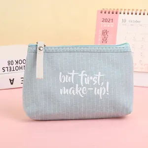 Light blue striped canvas makeup bag with 'but first, make-up!' text and zipper