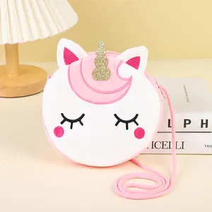 Detail of cute unicorn plush crossbody bag with embroidery and golden horn on a desk