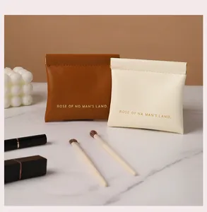 Close-up of portable leather makeup bags with metal squeeze closure in brown and cream