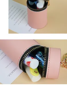 Détail du porte-monnaie cylindrique en cuir rose avec fermeture éclair dorée