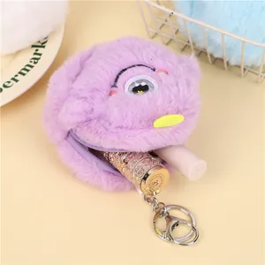 Detail of purple plush monster coin purse showing storage for lipstick and metal keychain
