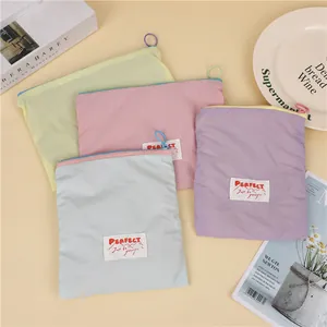 Detail of four macaron colored waterproof cosmetic bags with circular zipper pull and woven label