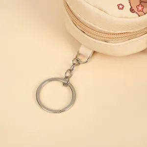 Detailed close-up of a cute beige capybara coin purse with zipper and silver keychain