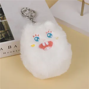Detail of white plush monster keychain showing blue eyes and embroidered toothy face