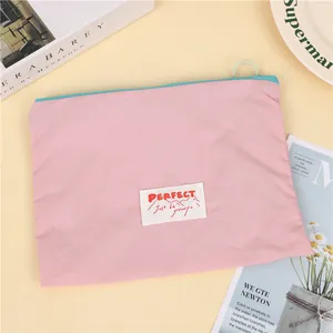 Detail of pink waterproof makeup bag with blue zipper and Perfect logo patch