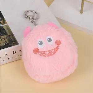 Close-up of pink plush monster keychain with soft fur, embroidered face and silver metal clasp
