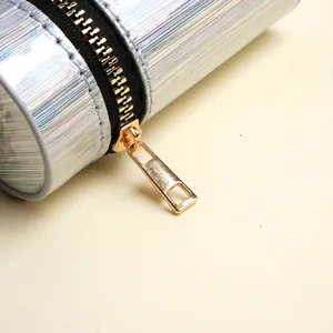 Detail van de laserzilveren cilindrische opbergtas met strepen en gouden metalen rits