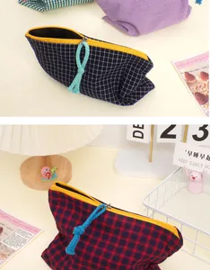 Detail of checkered makeup bag with vibrant yellow zipper and blue woven pull strap